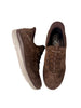 A pair of brown suede slip-on sneakers with lace-up detailing and thick white soles, displayed on a plain off-white background.